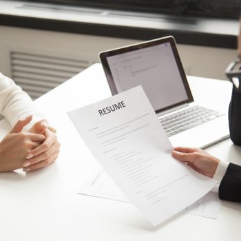 Company representatives reading applicant resume at hiring Hablemos del índice de rotación de personal.