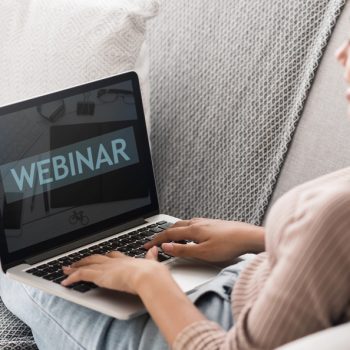 Student Girl Typing on Laptop with text on screen Webinar: Anheuser-Busch InBev: Comunidad de Mejora Continua